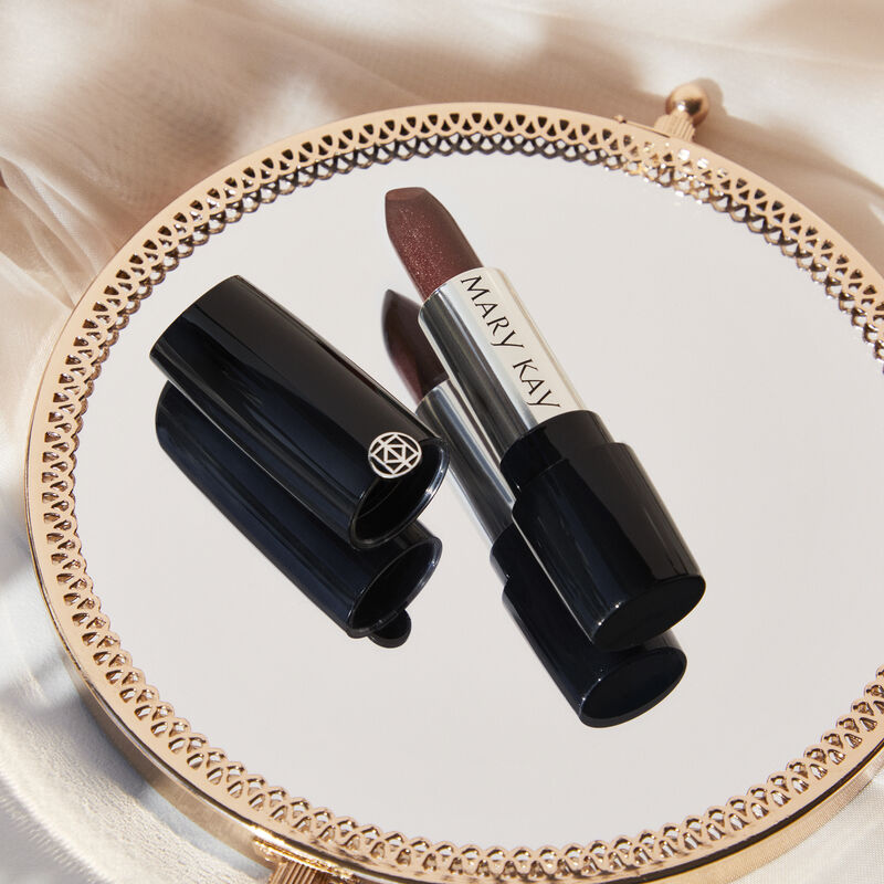 Uncapped tube of Mary Kay Gel Semi-Shine Lipstick in Downtown Brown on gold mirror